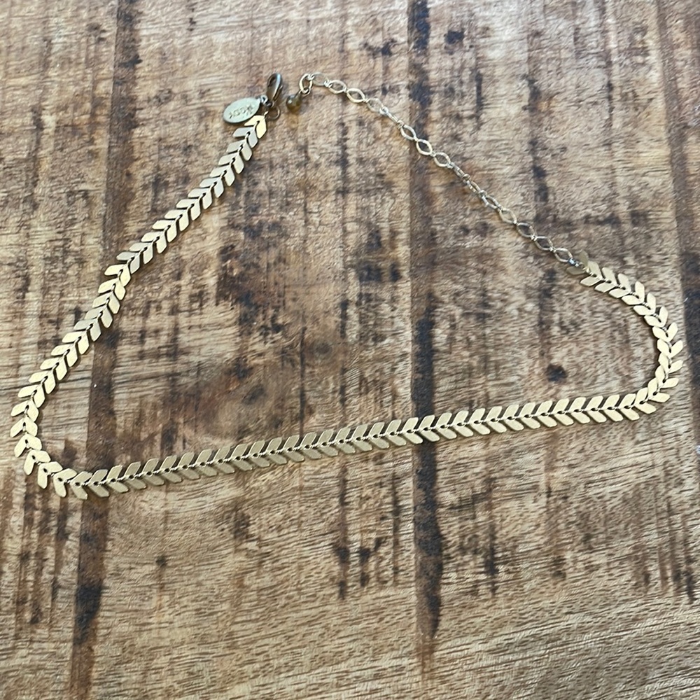 Gold tone choker with arrow detail.